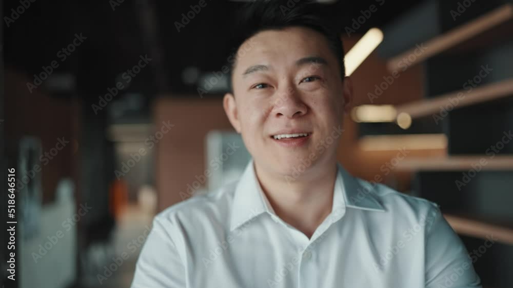 Smiling Asian brunet businessman looking at the camera and holding hands in the office 