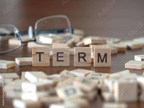 term word or concept represented by wooden letter tiles on a wooden table with glasses and a book