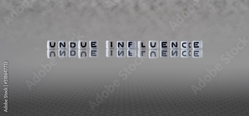 Photos undue influence word or concept represented by black and white letter cubes on a