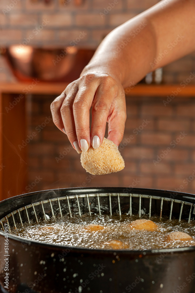 Deep frying brazilian croquettes stuffed with chiken in boiling soybean