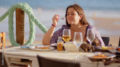 Family and friends gathered for lunch enjoying a delicious paella in a bar on the beach - happy little kids playing around the table after eating, eating dessert and ice cream © Quality Stock Video