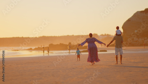 Wonderful family - father, mother and 4 sons (1-8 years old) - walk along one of the most beautiful beaches of Cádiz at sunset - they love and hug each other, look after their children