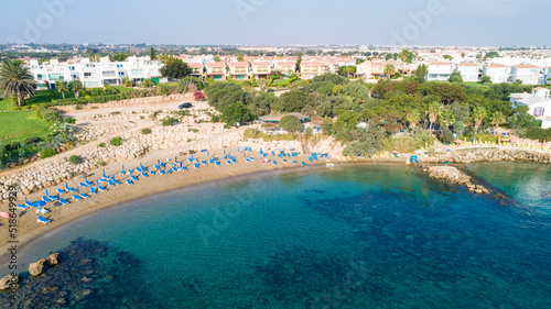 Aerial bird's eye view of Sirena beach in Protaras, Paralimni, Famagusta, Cyprus. The famous Sirina bay tourist attraction with sunbeds, golden sand, restaurant, people swimming in the sea from above.