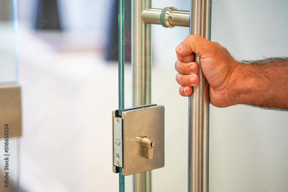 Male hand open the office glass door. Male hand open door knob. Man hand prepare to open the door to entering an office background - obrazy, fototapety, plakaty 