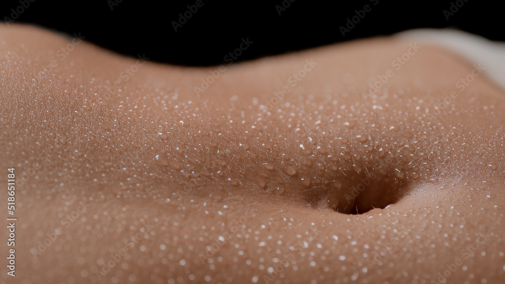Fototapeta premium Macro shot of slim white-skinned woman's wet good-looking clean flat belly on black background | Wet skin texture shot for healthy body concept