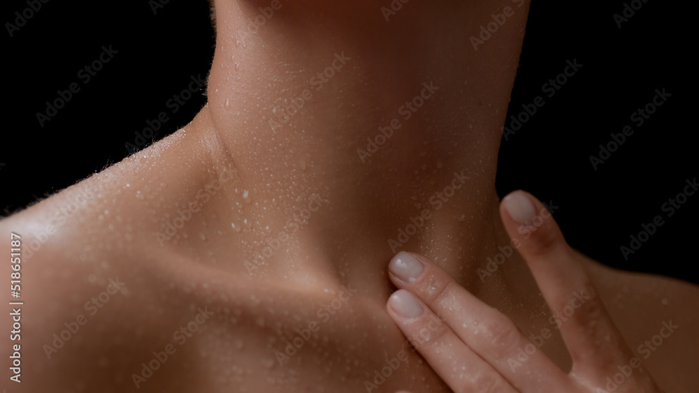 Macro shot of good-looking young slim white-skinned woman touches her wet body on black background | Body hydration concept Macro shot of good-looking young slim white-skinned woman touches her wet body on black background | Body hydration concept
