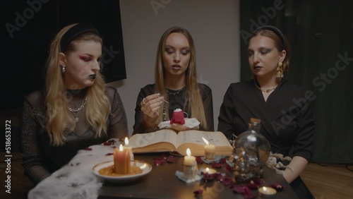 4K. Three female witches in a dark room insert needles into a voodoo doll