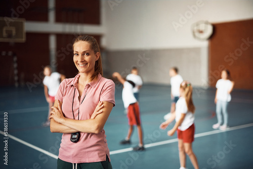 Fototapeta Naklejka Na Ścianę i Meble -  Portrait of PE teacher standing with her arms crossed at school gym and looking at camera.