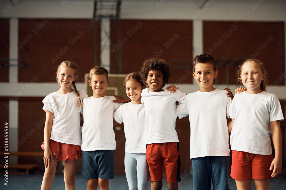 Group of happy school kids on PE class at school gym looking at camera.