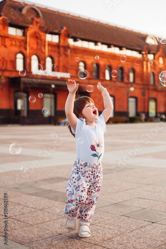 little girl playing on the street with blowing soap bubbles