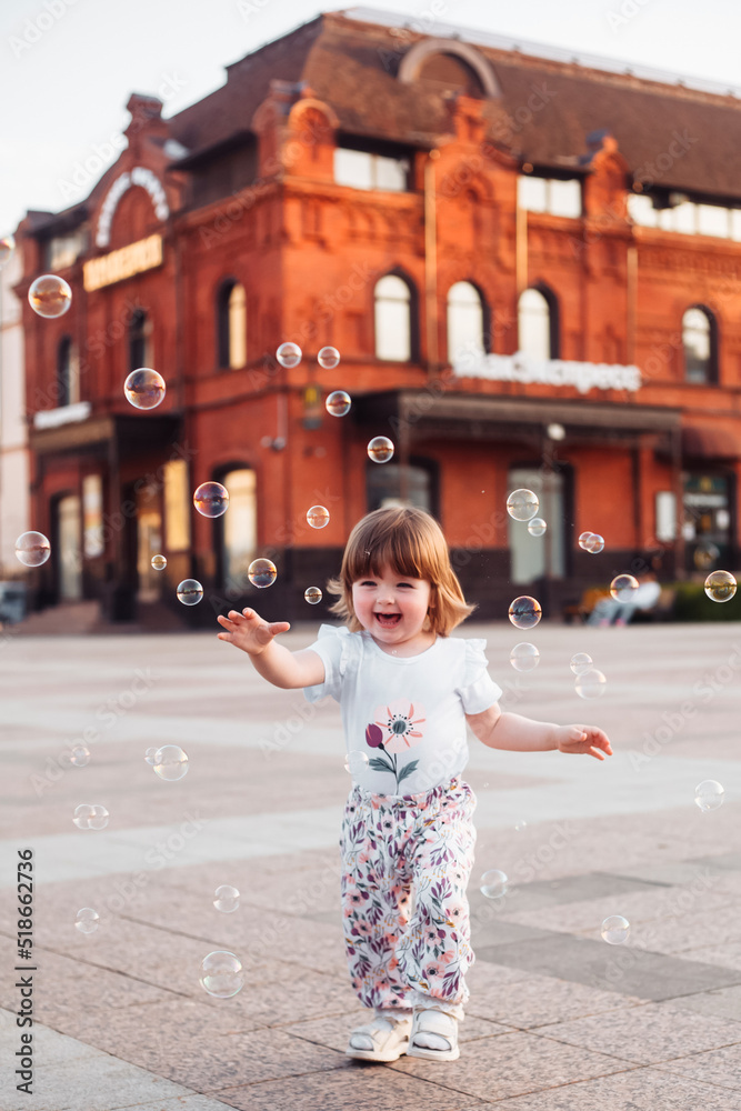 little girl playing on the street with blowing soap bubbles little girl playing on the street with blowing soap bubbles