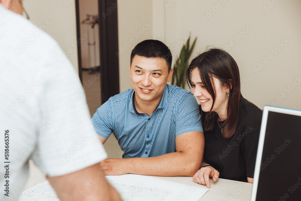 A happy couple signs a contract together in the office. a man and a woman buy an apartment and sign a contract.