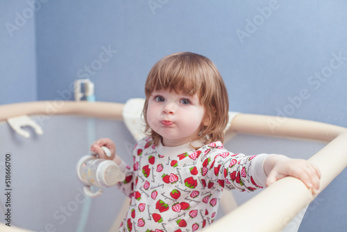 little baby girl in playpen with bottle of water photo