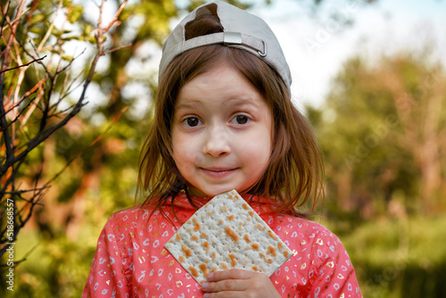 Satisfied girl in a fashionable cap eats matzo in nature
