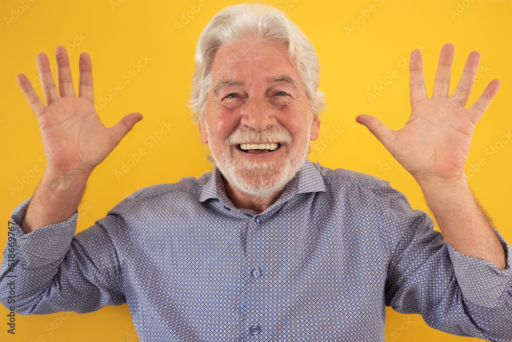 Portrait of beautiful happy funny senior bearded man looking at camera with open hands, standing on yellow background Portrait of beautiful happy funny senior bearded man looking at camera with open hands, standing on yellow background