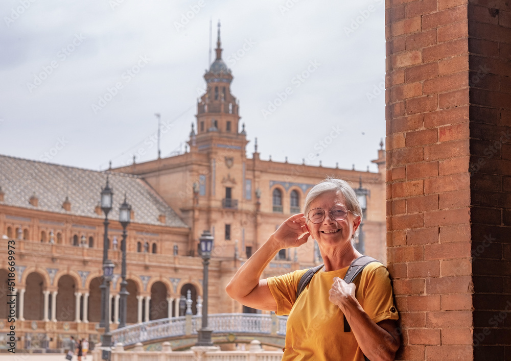 Obraz premium Happy senior woman traveling in Seville, Spain visiting famous places - attractive elderly traveler enjoying summer and cultural vacation