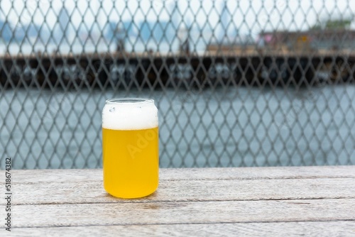 Valokuvatapetti Light lager beer in a glass on a pier