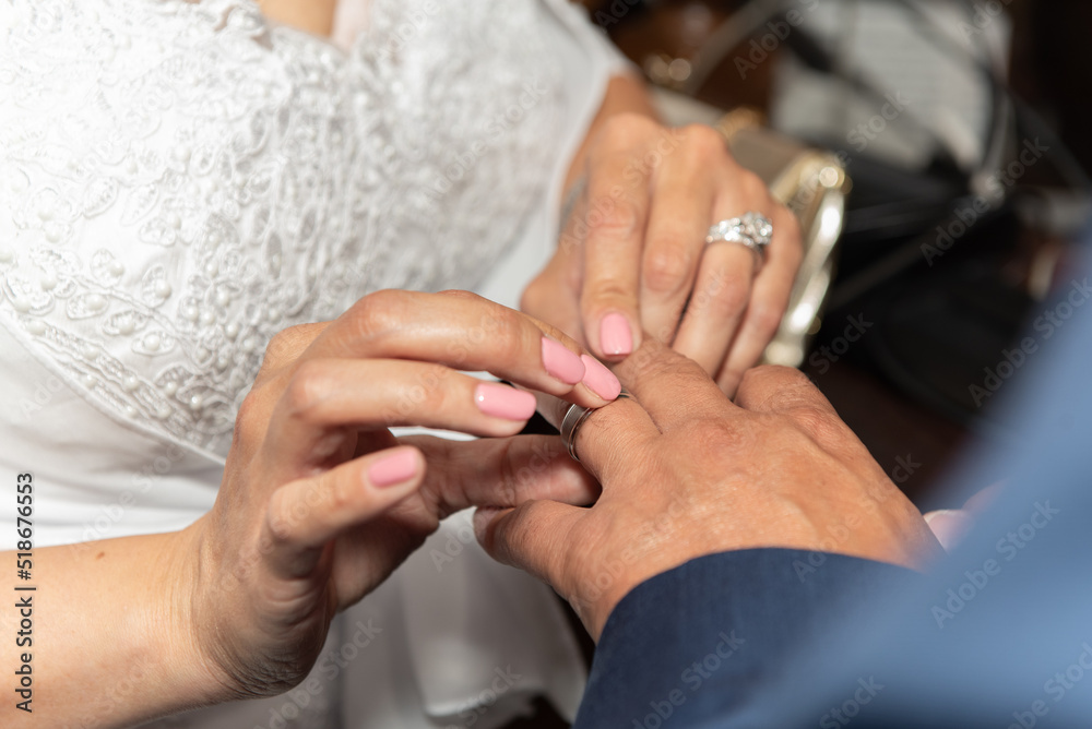 Fototapeta premium Bride placing ring on finger of the groom during the wedding ceremony of marriage
