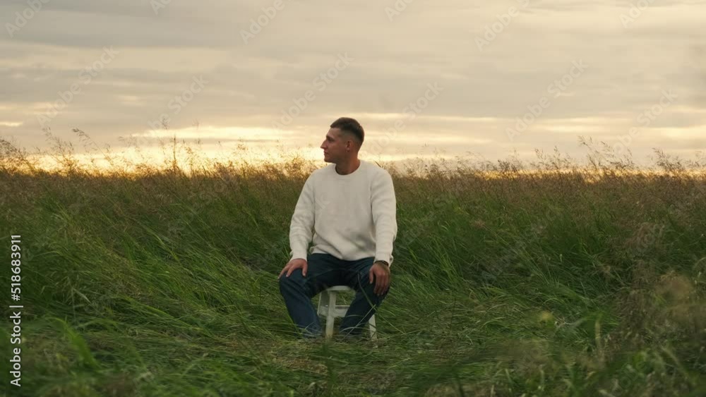 A pensive guy is sitting among a field outdoors. Loneliness. A pensive guy is sitting among a field outdoors. Loneliness.