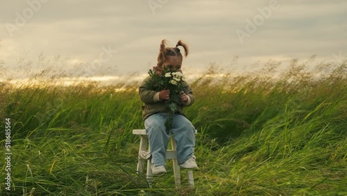 Funny girl sits on a chair with flowers in her hands. Outdoors.