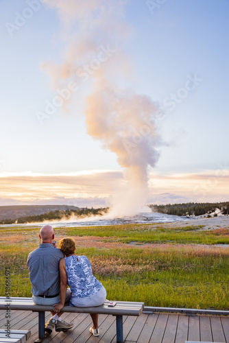 Tablou pe pânză Old couple watching the Old Faithful geyser during sunset