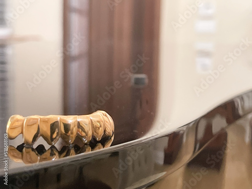 gold teeth grills sitting on piano closeup music success rich money