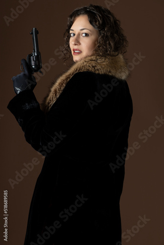 Wallpaper Mural A 1920s woman wearing a black velvet coat with a fur collar and holding a gun Torontodigital.ca