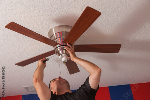 Man installing a ceiling fan in a bedroom photo