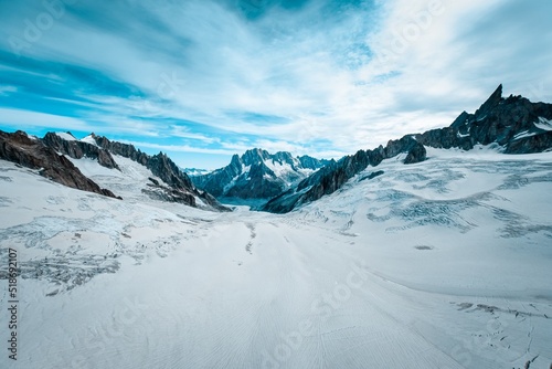 Beautiful wide shot of ruth glaciers covered in snow under a blue sky with white clouds