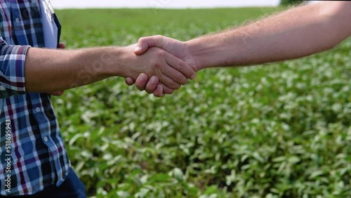 Handshake on soybean field. Two farmers standing outdoors in soy field in late summer shaking hands on deal photo