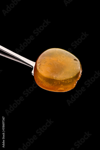 A fresh, opaque coin of Rosin on a titanium dab tool with a black background.  photo