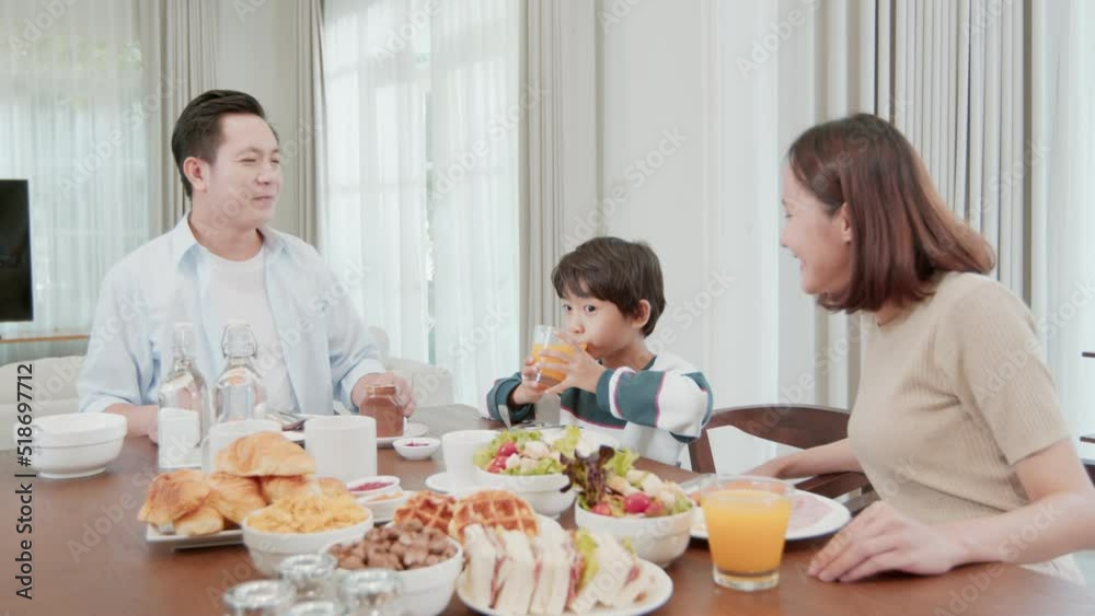 Happy family enjoy eating breakfast, Asian man and woman, husband and wife eating food with young boy and talking together Happy family enjoy eating breakfast, Asian man and woman, husband and wife eating food with young boy and talking together