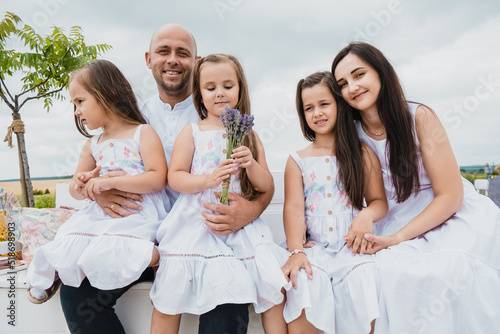 Portrait of a happy smiling family.Loving dad and mom hug and kiss their children. Children hold a bouquet of lavender in their hands.
