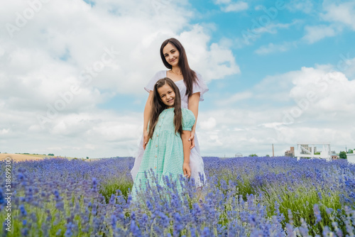 Happy cheerful family resting in nature.Mother and daughter are having a good time in the flower field.

