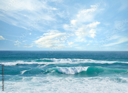 Fototapeta Naklejka Na Ścianę i Meble -  Landscape banner view of waves rolling onto the seashore against a cloudy blue sky in summer. Peaceful scenic view of clear beach water in a tropical area. Relaxing natural environment on the coast
