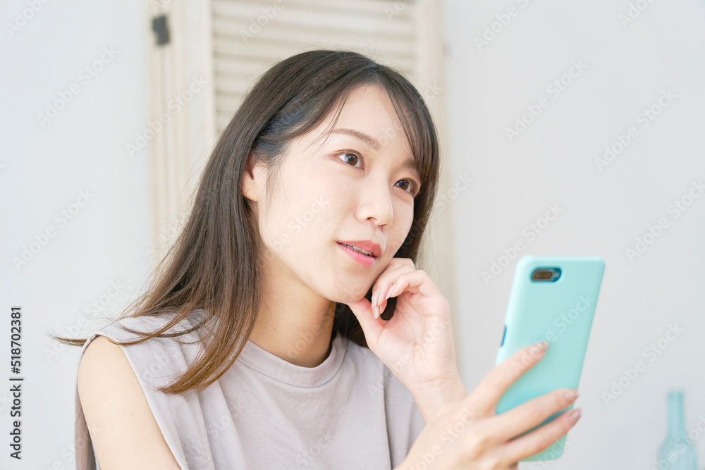 リビングでスマホを持って想像する女性 リビングでスマホを持って想像する女性