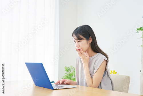 リビングで心配そうにノートパソコンを見る女性