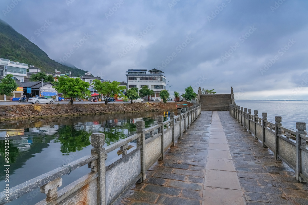 Obraz premium The street view and the natural landscape of the ancient stone arch bridge on the Erhai sea in Yunnan Province, China