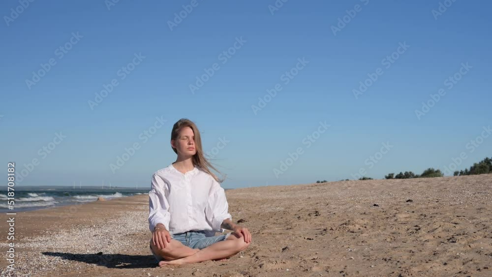 Girl meditating by the sea. Wind shakes long blond hair Girl meditating by the sea. Wind shakes long blond hair