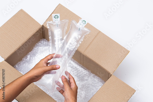 Hands holding airbag cushion for protecting the goods from delivery in opened the brown cardboard parcel box photo