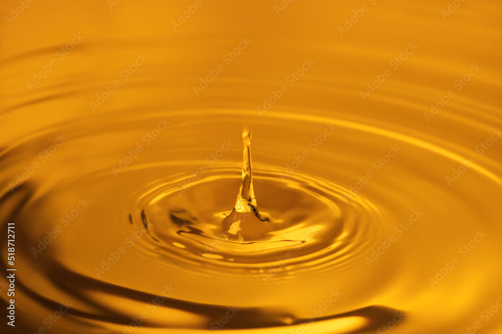 Splash of golden oily liquid with drop as background, closeup