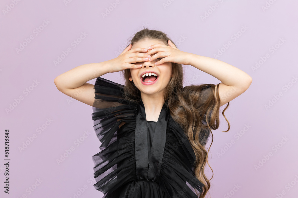 The child covers his eyes with his hands. The happy little girl has covered her eyes with her