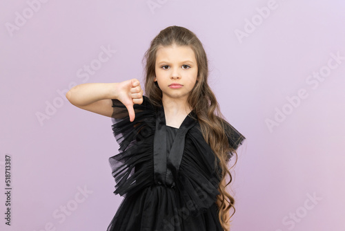 The child shows a thumbs-down dissatisfaction. The little girl protests and shows her displeasure.
