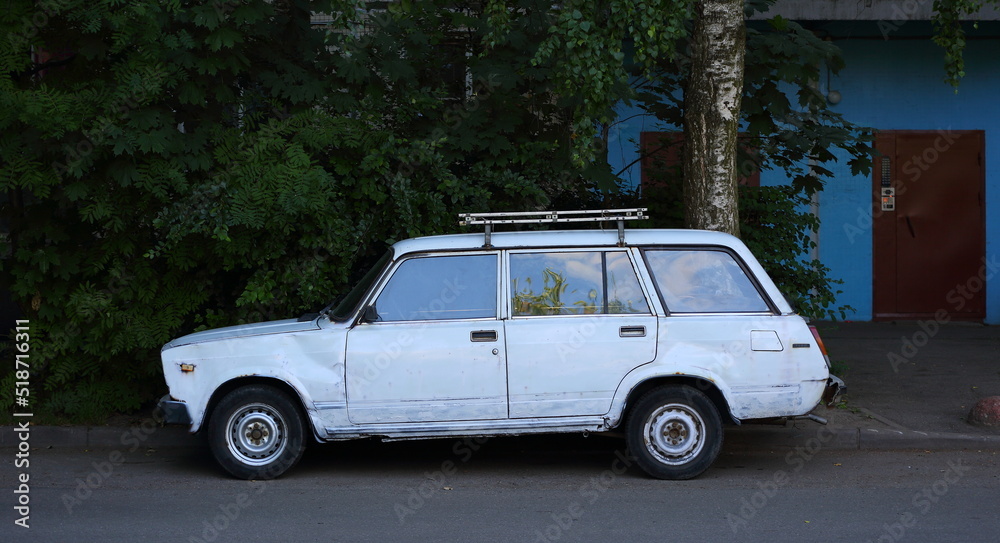 An old white Soviet car in the courtyard of a residential building, Iskrovsky Prospekt, St. Petersburg, Russia, July 2022