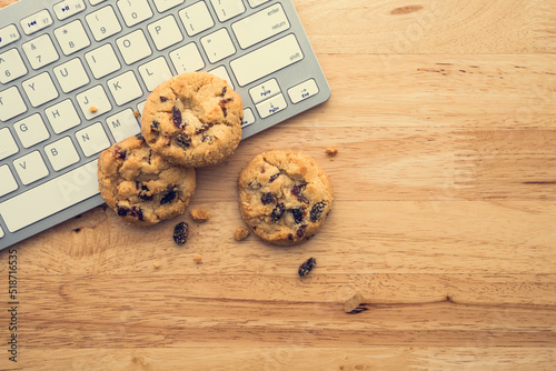 Fotobehang Flat lay of white chocolate chip cookies on keyboard computer on wooden table background copy space