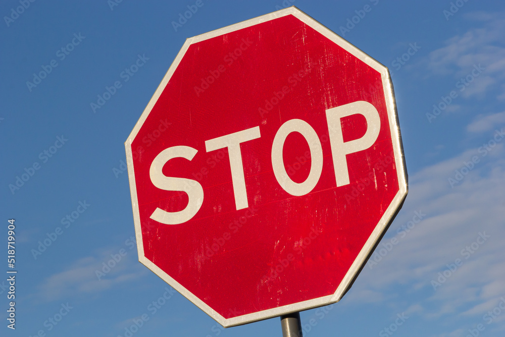 Red Stop Sign with Blue Sky and Clouds Background