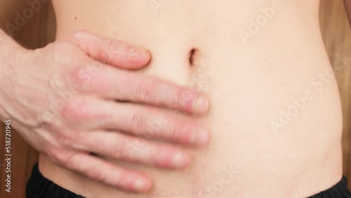 Abdominal pain. A young man touches his bare stomach with his hand. Discomfort in the epigastric region. Spasm feeling in the abdomen. photo