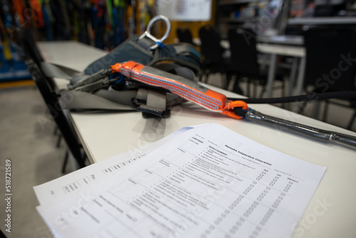 Harness inspection checklist paper placing on the table, defocused harness, shock absorber lanyards fall arrest fall protection safety assessment prior to work approval sign off of each task 