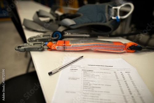 Shock absorber lanyards fall arrest fall protection checklist paper black pen placing on the table safety assessment with defocused safety harness prior to daily work approval sign off each task 