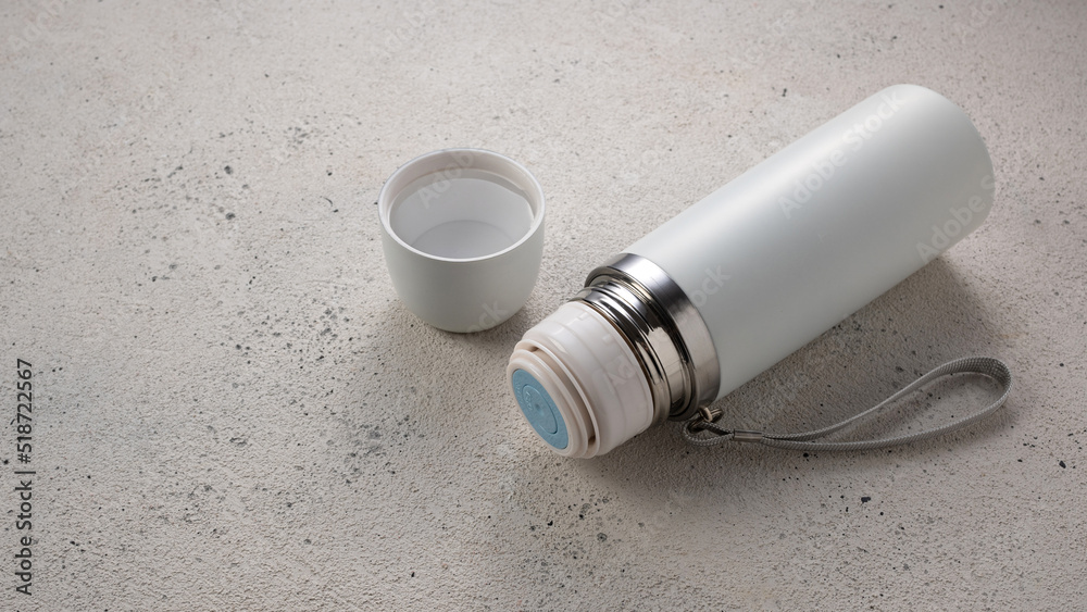 White thermos for drinks for travel and sports on light background, empty place for inscription White thermos for drinks for travel and sports on light background, empty place for inscription